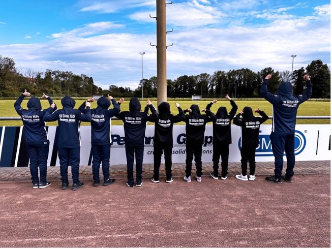 Die E-Junioren zeigen die Rückseite ihrer neuen Trainingsanzüge.